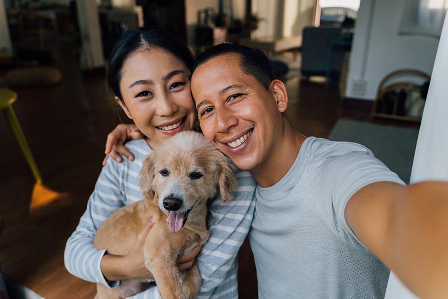 Contact Us - Happy Couple Takes a Selfie With Their Golden Retriever Puppy